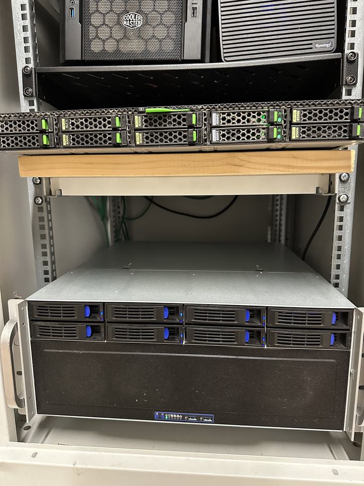 Close-up of a rack with a Synology NAS, a 1U server with drive bays and a 4U server chassis with blue drive caddies.
